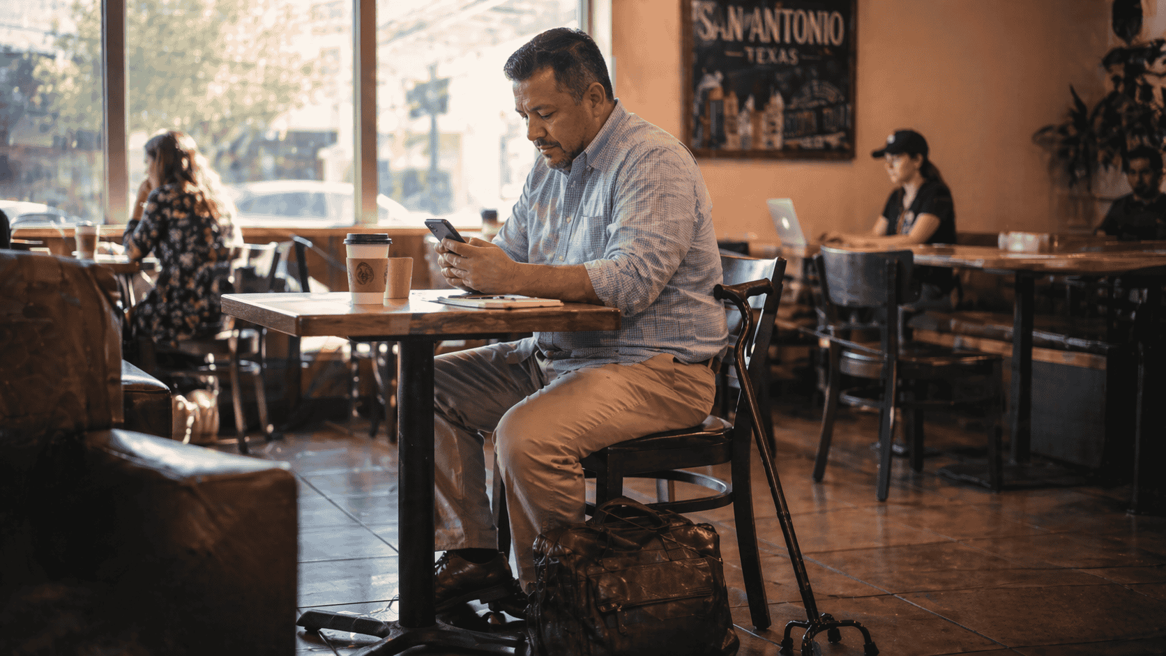 Middle-aged Texas man working at a San Antonio coffee shop, with a quad cane leaning against his chair.