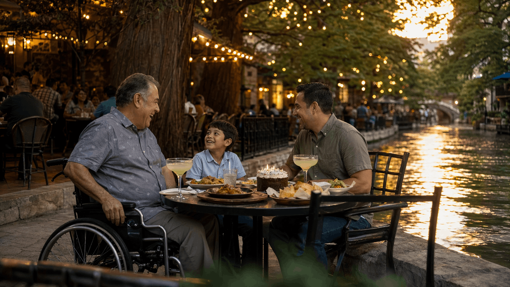 A Texas grandfather in a wheelchair shares dinner with his son and grandson at a San Antonio River Walk cafe at golden hour.